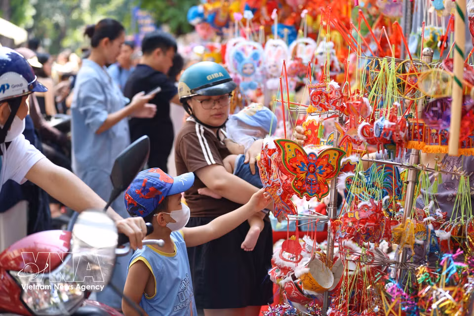 Familles et enfants déambulent parmi les étals colorés de la rue Hang Ma à l’approche de la fête.