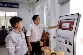 Des agents du Centre de services administratifs publics du quartier de Long Xuyen (province d'An Giang) guident des gens dans leurs démarches en ligne sur le portail national des services publics. Photo : VNA