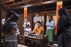 Des touristes assistent à une démonstration de calligraphie lors d'une visite nocturne du Temple de la Littérature à Hanoï. Photo : VNA