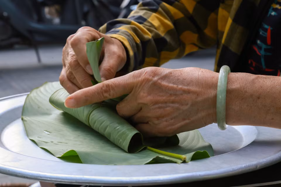 Le produit fini doit être obligatoirement enveloppé afin qu’il ne sèche pas et ne perde pas sa couleur verte. Le parfum du côm et celui des feuilles de lotus fraîches se marient bien, donnant une saveur particulière au côm de Hanoï. Photo : VNA
