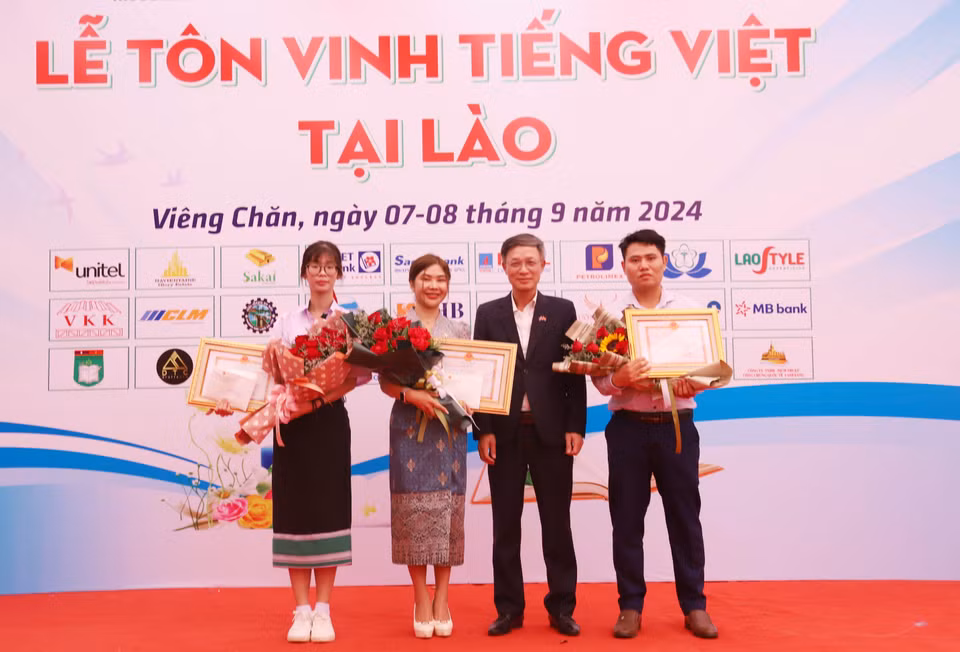 Le chargé d'affaires de l'ambassade du Vietnam au Laos, Phan Minh Chien (2e, gauche), remet des satisfecit et des récompenses aux trois finalistes du concours "À la recherche des ambassadeurs du vietnamien à l'étranger en 2024". Photo : VNA