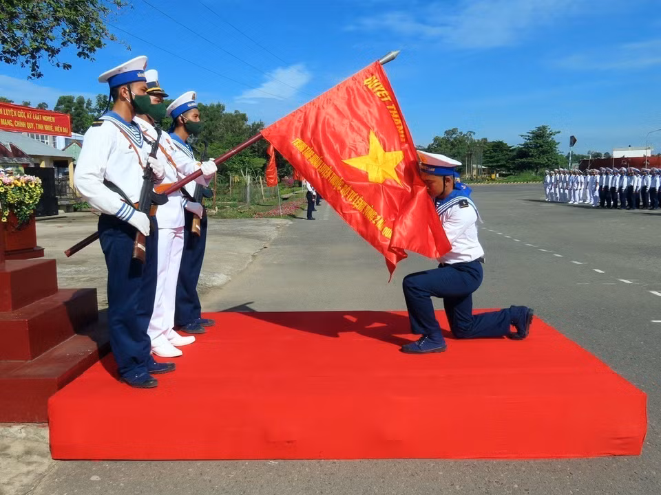 Les nouveaux soldats effectuent la cérémonie du baiser du drapeau militaire lors de la cérémonie du serment avant de partir en service dans les unités de la région navale 2. Photo: Doan Manh Duong/VNA