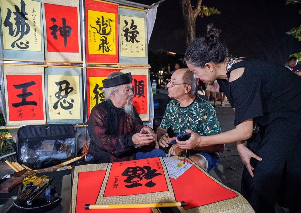 Touristes étrangers demandent des lettres dans la rue piétonne autour du lac Hoan Kiem. Photo : VNA