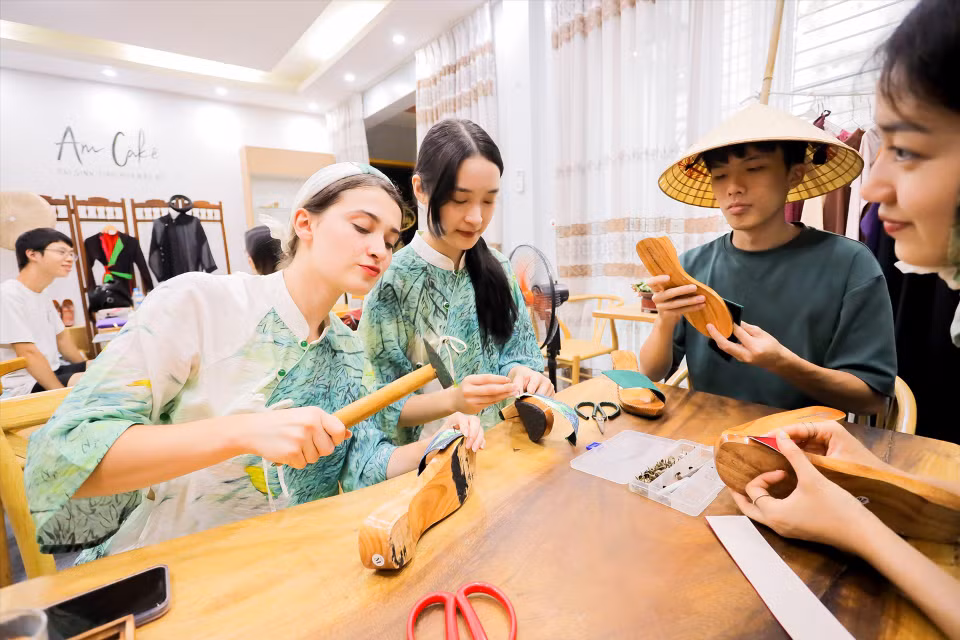 Des visiteurs internationaux s'initient à la fabrication artisanale de sandales en bois vietnamiennes. ​