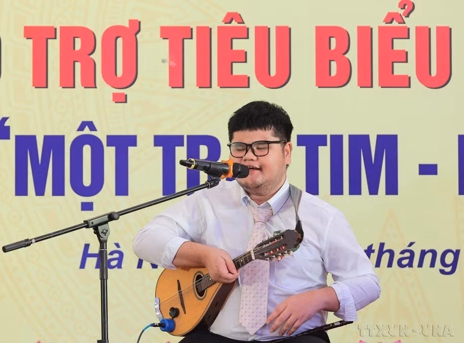 Bui Ngoc Thinh, non-voyant originaire de la province de Khanh Hoa, qui maîtrise 14 instruments musicaux et lauréat de multiples distinctions, s'exprime lors d’une conférence louant les personnes en situation de handicap, les orphelins et les mécènes exemplaires, dans le cadre du programme "Un cœur - Un monde" (Mot trai tim – Mot the gioi). Photo : VNA