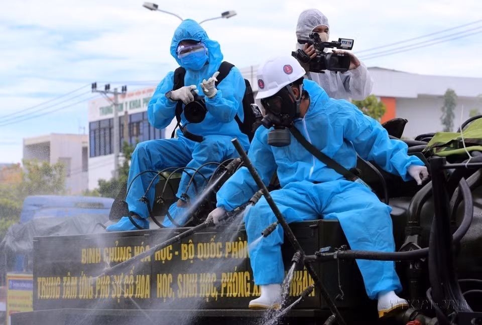 Un journaliste de la filiale du Centre de télévision de la VNA (VNEWS) à Da Nang travaille à l'arrière d'un véhicule pour pulvériser du désinfectant dans les zones à haut risque d'infection au COVID-19 de l’arrondissement de Son Tra, ville de Da Nang. Photo : VNA