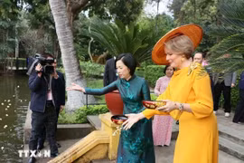 La Reine Mathilde et Mme Nguyen Thi Minh Nguyet donnent la nourriture aux poissons dans l'étang de l'Oncle Ho. Photo : VNA