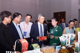 Nguyen Minh Vu, ambassadeur du Vietnam au Cambodge, et des entreprises cambodgiennes visitent le stand vietnamien. Photo : VNA