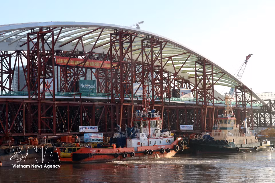 Les remorqueurs acheminent progressivement la travée du pont vers son emplacement de montage, entre les deux parties déjà construites.