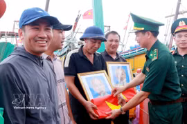 La Fédération et le Commandement provincial des gardes-frontières ont remis aux pêcheurs 400 drapeaux nationaux et 120 portraits du Président Hô Chi Minh. Photo: VNA