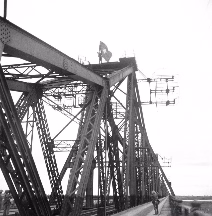 Les soldats plantèrent le drapeau national sur le toit du pont Long Bien. Photo : Archives-VNA