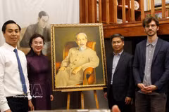 La directrice du site des vestiges du président Hô Chi Minh dans la zone du Palais présidentiel, Lê Thi Phuong, le directeur du Musée de l’Histoire vivante, Thomas Le Goff (premier rang, à droite) et d’autres membres de la délégation posent avec un grand portrait du Président Hô Chi Minh. Photo : VNA