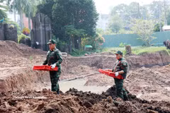 Les membres de l’équipe K74 transportent les restes de martyrs depuis le site de fouilles vers un local destiné au recueil et au stockage d’échantillons, afin de faciliter l’identification des martyrs. Photo : VNA