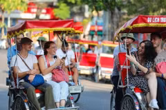 Des touristes étrangers prennent un cyclo-pousse pour découvrir le Vieux quartier de Hanoi. Photo : VNA