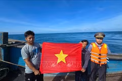 Deux pêcheurs exhibent le drapeau rouge à étoile jaune. Photo: VNA
