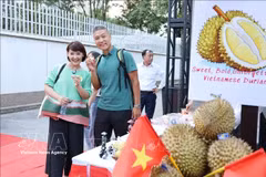 Deux touristes se font photographier avec des durians lors d'un événement vietnamien promouvant ce fruit savoureux. Photo: VNA