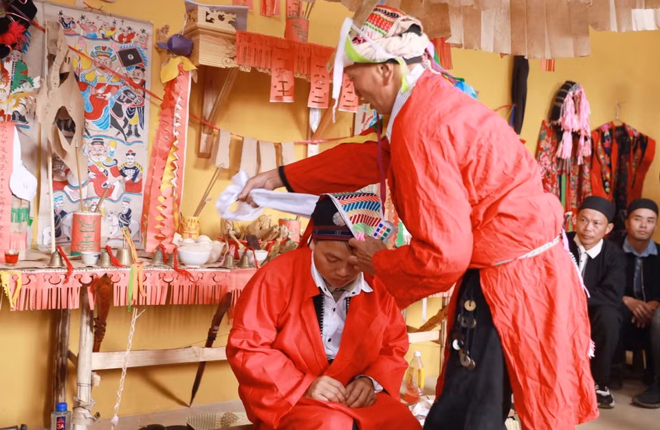 Le sorcier enveloppe la tête du jeune homme d'un foulard, l'initiant ainsi à la cérémonie de passage à l'âge adulte. Photo: VNA