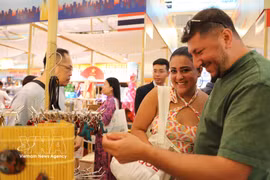 Des visiteurs étrangers apprécient les produits artisanaux présentés lors de l’événement. Photo: VNA