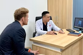Le docteur Do Lenh Hung (à droite), chef du service de chirurgie reconstructive urétrale de l'hôpital Binh Dan réalise un examen médical auprès du patient, D.F. (47 ans, de nationalité américaine) après une chirurgie reconstructive urétrale. Photo : hôpital Binh Dan