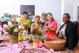 Des visiteurs découvrent l'art de parfumer le thé au lotus de Quảng An. Photo: VNA