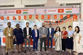 Le conseiller commercial Bùi Trung Thuong (4e de gauche à droite) et des invités nationaux et étrangers visitant le stand. Photo: VNA