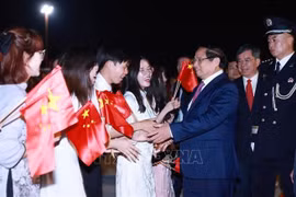 Le Premier ministre Pham Minh Chinh est accueilli à l'aéroport par des représentants de la communauté vietnamienne en Chine. Photo : VNA