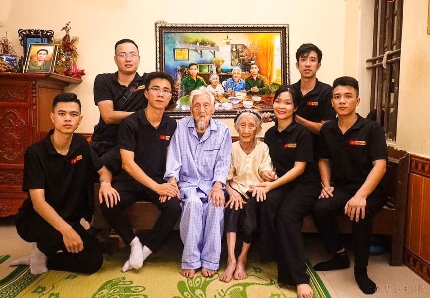 Phung Quang Trung (2e, à droite) et l'équipe de restauration de photos Skyline ont remis en état des milliers de photos de martyrs pour rendre hommage à ceux qui se sont sacrifiés pour l'indépendance et la liberté de la Patrie. Sur la photo : remise à la mère héroïne vietnamienne Nguyên Thi Ngach et à son mari, une photo simulant un repas de retrouvailles avec leurs deux fils morts au combat. Photo : VNA