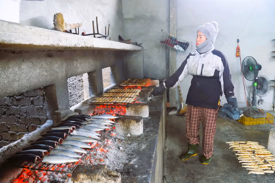 Le grilladin doit surveiller le foyer en permanence afin d'ajuster le charbon et maintenir une chaleur uniforme, garantissant une cuisson rapide et homogène. L'ajout régulier de charbon permet de maintenir une intensité de feu constante pour une cuisson optimale des poissons. Photo : VNA