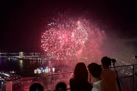 Des touristes regardent un feu d’artifice dans la ville de Dà Nang. Photo : VNA