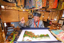  Un artisan brode une peinture dans l'espace d'exposition. Photo : VNA