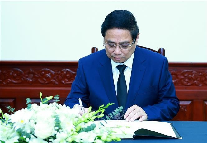 Le Premier ministre Pham Minh Chinh écrit dans le registre de condoléances. Photo : VNA