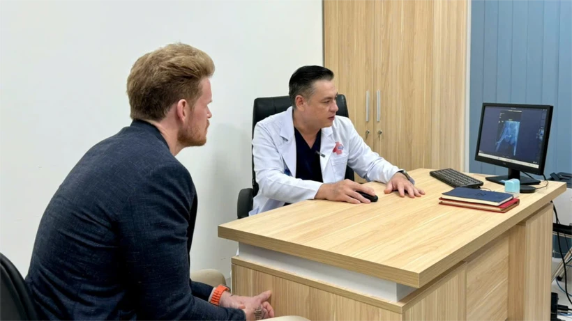 Le docteur Do Lenh Hung (à droite), chef du service de chirurgie reconstructive urétrale de l'hôpital Binh Dan réalise un examen médical auprès du patient, D.F. (47 ans, de nationalité américaine) après une chirurgie reconstructive urétrale. Photo : hôpital Binh Dan