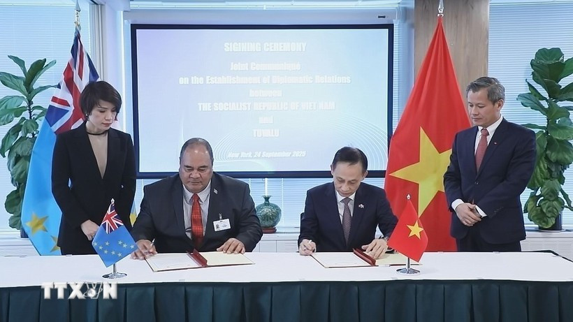 Le Hoai Trung (droite), ministre vietnamien par intérim des Affaires étrangères et Paulson Panapa, ministre des Affaires étrangères, du Travail et du Commerce de Tuvalu, signent un communiqué conjoint sur l’établissement des relations diplomatiques entre la République socialiste du Vietnam et Tuvalu. Photo : VNA