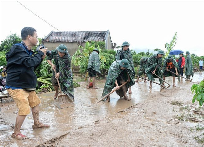 Le journaliste Danh Lam travaille sur place sur les activités visant à surmonter les conséquences des pluies et des inondations dans le village de Kha La, commune de Tan Lap, Luc Ngan, Bac Giang. Photo de : VNA 2.jpg