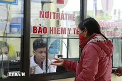 Une femme s'inscrit à un examen médical à l'aide de sa carte d'assurance maladie. Photo: VNA