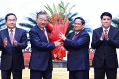 Le Premier ministre Pham Minh Chinh (2e à partir de la droite) offre des fleurs à To Lam (2e à partir de la gauche) après son élection au poste de secrétaire général du Comité central du Parti du 13e mandat. Photo: VNA