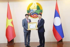 Le vice-Premier ministre et ministre des Affaires étrangères du Laos, Saleumxay Kommasith (droite), remet la noble distinction à l'ambassadeur Nguyen Ba Hung. Photo : VNA
