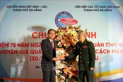 Un représentant du Comité de liaison des volontaires et experts militaires vietnamiens (à droite) offre un annuaire du 75e anniversaire anniversaire de la Journée traditionnelle des soldats volontaires et experts vietnamiens au Lao au consul général du Laos à Da Nang. Photo : VNA