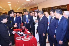 Le président du Comité populaire de Hanoï, Tran Sy Thanh, et d'autres délégués visitent la zone d'exposition des produits et services au service de la construction de villes intelligentes. Photo: VNA