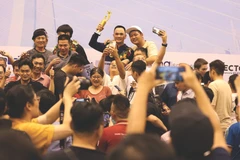 Brandissant le trophée de la Coupe du monde de billard carambole à trois bandes, Trân Duc Minh est entouré de ses fans. Photo : CTV/CVN