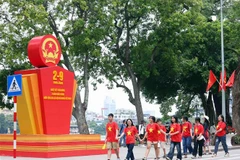 Des jeunes marchent en liesse devant un paneau célébrant la 79e Fête nationale du Vietnam, près du lac Hoàn Kiêm, à Hanoi. Photo : VNA