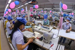 Des ouvriers au travail dans une entreprise de confection. Le taux de localisation de nombreux secteurs industriels clés, tels que l’habillement, est faible, dépendant fortement de l’importation de matières premières. Photo : VNA