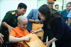 La vice-présidente Vo Thi Anh Xuan offre un cadeau à une victime du Centre de soins et de traitement des victimes de l’agent organe/dioxine de Hanoï. Photo: VNA