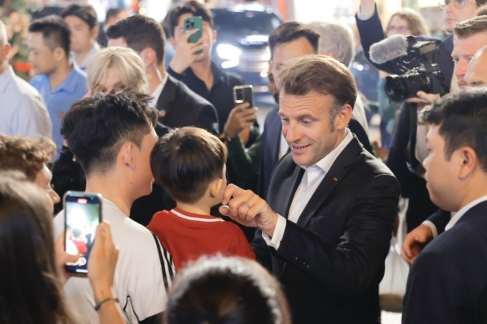 Le président français, Emmanuel Macron, et sa première dame rencontrent des habitants lors d'une promenade dans le Vieux Quartier de Hanoï, le soir du 26 mai. Photo: VNA