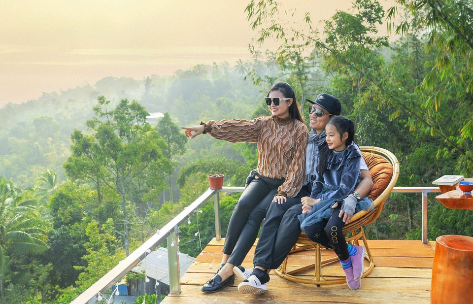 Une famille de touristes savoure du thé en admirant le lever du soleil au sommet du mont Câm. Photo: VNA