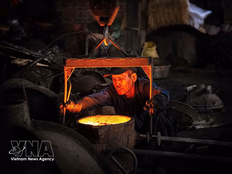 Après avoir versé le fonte en fusion, l'ouvrier retire le moule pour récupérer le produit fini. Photo: VNA