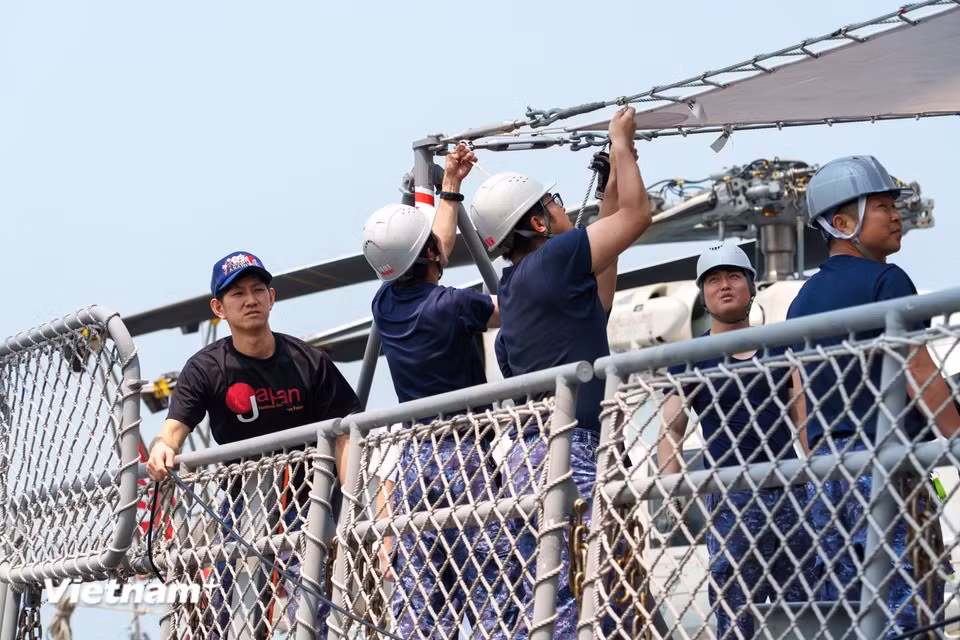 Des marins japonais installent une bâche de protection sur le pont avant les activités d’accueil et d’échange. Photo : VietnamPlus
