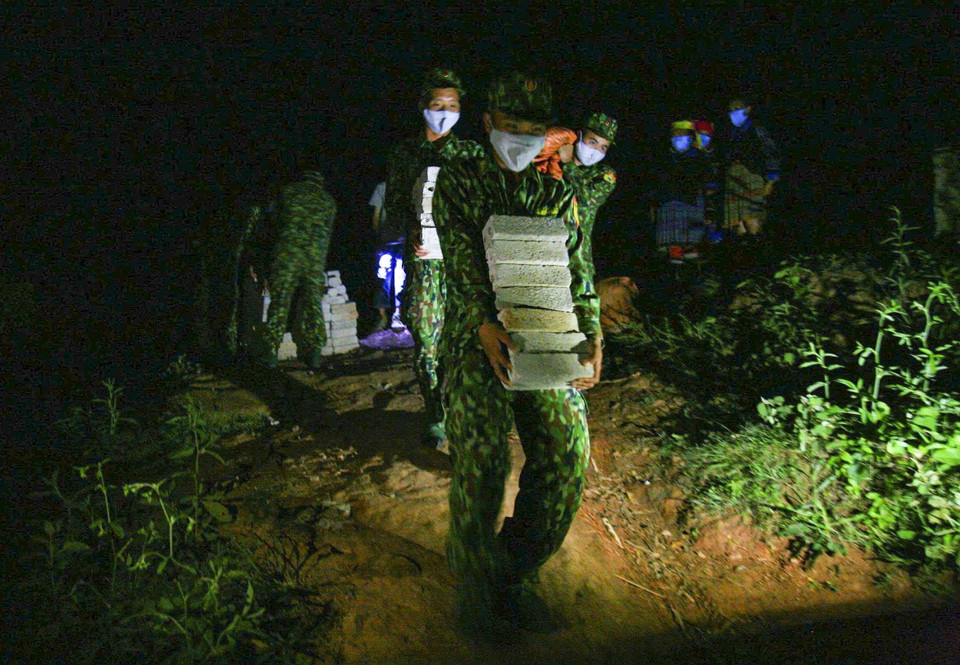 De nuit, des soldats du poste de garde-frontière de Na Bung acheminent des matériaux de construction, s'engageant à offrir un foyer aux familles les plus défavorisées de la région. Photo: VNA