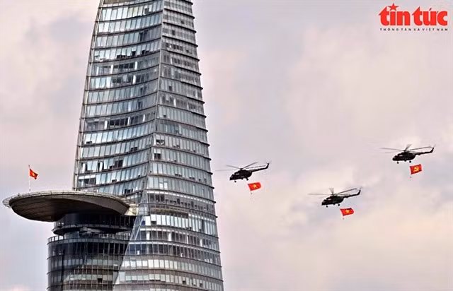 Les hélicoptères survolent la tour financière Bitexco, dans le 1er arrondissement de la mégapole du Sud. Photo : Baotintuc.vn/VNA Chaque hélicoptère transportait un drapeau d’environ 20 m², équipé d’un contrepoids de 120 kg au pied du câble de levage pour garantir sa tension pendant le vol.