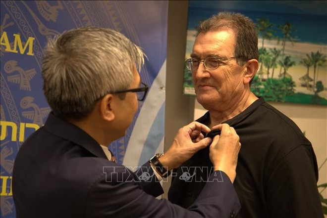 L'ambassadeur Ly Duc Trung remet l'insigne du Vietnam au professeur Benjamin Peretz, dont 16 photos en noir et blanc sont exposées à l'exposition. Photo : VNA 2.jpg